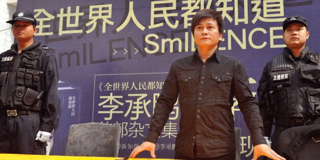 Chinese writer Li Chengpeng, looked upon by many as a a highly influential Chinese blogger and social commentator, is protected by bodyguards as he attends a promotional event of his new book 'SmILENCE' on January 26, 2013 in Kunming, southwest China's Yunnan province. Li was attacked by Maoists earlier at his book signings in Beijing and Shenzhen, forcing him to cancel two others in Guangzhou and Changsha. The Maoists take offence to Li's caustic essays and comments about the Communist Partyâs governance. Li has previously been punched in the head at a previous signing. CHINA OUT AFP PHOTO (Photo credit should read STR/AFP/Getty Images)