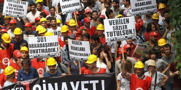 Turkish miners, who survived the May 2014 devastating coalmine blast of Soma, take to the streets for a protest against the government in Ankara on June 16, 2014. Miners asked Turkish prime minister Recep Tayyip Erdogan to keep his promises. CCTV images of the mine Soma, where 301 miners died in the accident, showed that two fires broke out just days before the explosion in the mine. The banner in foreground reads 'Murder !'. AFP PHOTO/ADEM ALTAN (Photo credit should read ADEM ALTAN/AFP/Getty Images)