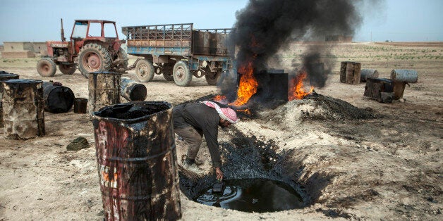 TO GO WITH AFP STORY BY JOSE MIGUEL CALATAYUDA picture taken on April 15, 2013 shows a Syrian man in the Al Raqqa countryside, who until three months ago was a farmer, pouring crude oil brought from Deir Ezzor province into a pit where it will be distilled as part of the refining process to produce fuel. Final products such as benzine and diesel are then sold to locals. Deir Ezzor contains the largest energy reserves in Syria, which produced some 420,000 of barrels of oil a day before the United States and the European Union banned the import of Syrian petroleum in 2011. AFP PHOTO/ALICE MARTINS (Photo credit should read ALICE Martins/AFP/Getty Images)