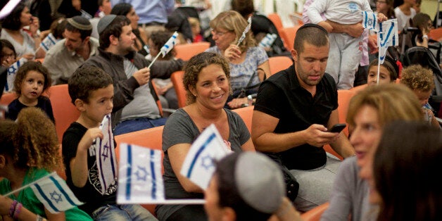 TEL AVIV, ISRAEL - JULY 16: (ISRAEL OUT) An estimated 400 new French Jewish immigrants wave Israeli flags during a welcoming ceremony after arriving on a flight from France on July 16, 2014 at Ben Gurion airport near Tel Aviv, Israel. Today Israel reportedly issued a warning to 100,000 residents of northern Gaza to evacuate their homes as it continues with planned airstrikes as part of operation 'Protective Edge'. Israeli Prime Minister Benjamin Netanyahu said he had 'no choice' but to expand and intensify the military operation in light of the refusal to ceasefire terms from Hamas officials. (Photo by Lior Mizrahi/Getty Images)