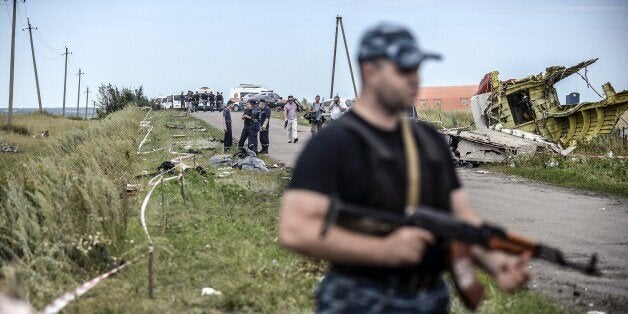 Armed pro-Russian separatists stand guard in front of the crash site of Malaysia Airlines Flight MH17, near the village of Grabove, in the region of Donetsk on July 20, 2014. The missile system used to shoot down a Malaysian airliner was handed to pro-Russian separatists in Ukraine by Moscow, the top US diplomat said Sunday. Outraged world leaders have demanded Russia's immediate cooperation in a prompt and independent probe into the shooting down on July 17 of flight MH17 with 298 people on board. AFP PHOTO/ BULENT KILIC (Photo credit should read BULENT KILIC/AFP/Getty Images)