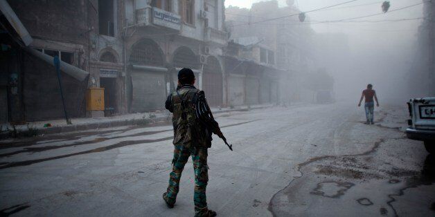 A rebel fighter stands on a street covered with dust following a reported air strike by Syrian government forces in the old city of Aleppo on July 21, 2014. Aleppo was Syria's most populous city before the conflict, but it is now a major battle zone split into areas controlled by the rebels concentrated in the east and those held by the government mainly in the west. AFP PHOTO / AHMED DEEB (Photo credit should read AHMED DEEB/AFP/Getty Images)
