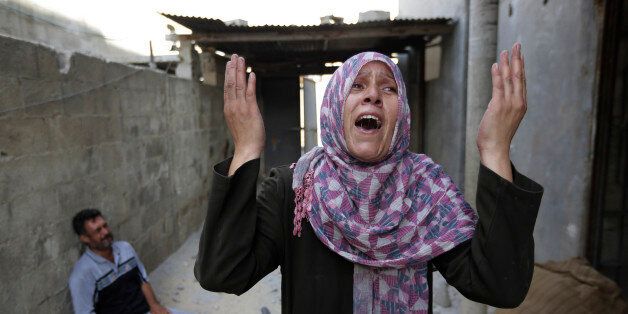 As her brother-in-law Mazen Keferna, background left, weeps, Palestinian Manal Keferna, 30, right, cries upon her return to the family house, destroyed by Israeli strikes in Beit Hanoun, northern Gaza Strip, Saturday, July 26, 2014. Thousands of Gaza residents who had fled Israel-Hamas fighting streamed back to devastated border areas during a lull Saturday, and were met by large-scale destruction: scores of homes were pulverized, wreckage blocked roads and power cables dangled in the streets. (AP Photo/Lefteris Pitarakis)