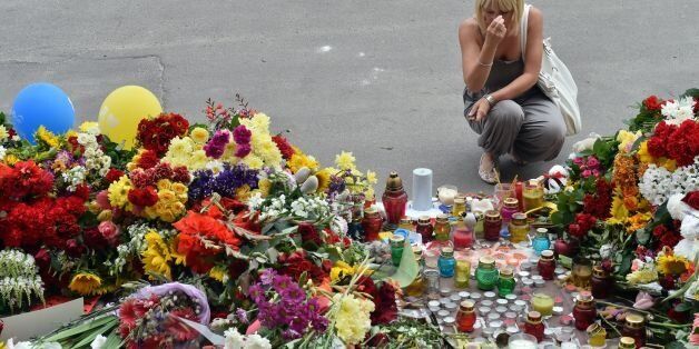 A woman crosses herself as people lay flowers and light candles in front of the Embassy of the Netherlands in Kiev on July 18, 2014, to commemorate passengers of Malaysian Airlines flight MH17 carrying 295 people from Amsterdam to Kuala Lumpur which crashed in eastern Ukraine. Ukraine's prime minister said Friday that pro-Russian separatist rebels that Kiev believes shot down a Malaysian airliner with 298 people on board should face an international tribunal in The Hague. AFP PHOTO/ SERGEI SUPINSKY (Photo credit should read SERGEI SUPINSKY/AFP/Getty Images)