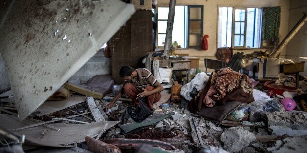 A Palestinian scout collects human remains from a classroom inside a UN school in the Jabalia refugee camp after the area was hit by shelling on July 30, 2014. Israeli bombardments early on July 30 killed 'dozens' of Palestinians in Gaza, including at least 16 at a UN school, medics said, on day 23 of the Israel-Hamas conflict. AFP PHOTO / MARCO LONGARI (Photo credit should read MARCO LONGARI/AFP/Getty Images)