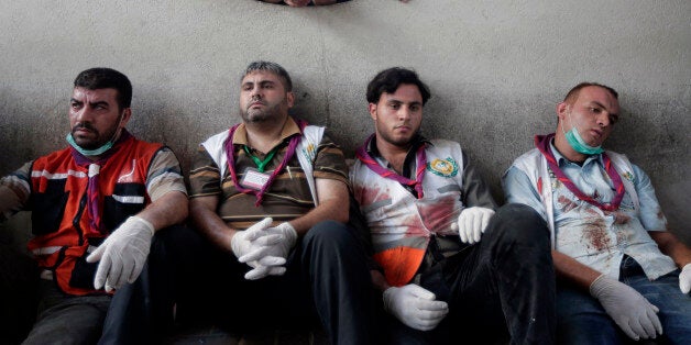 Palestinian medics take a break after carrying wounded people injured from an Israeli strike in Shijaiyah neighborhood, into