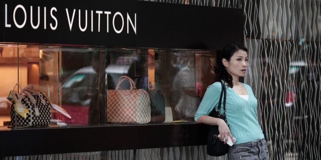 To go with Lifestyle-HongKong-China-luxury,FOCUS by Beh Lih YiThis picture taken on April 23, 2013 shows a Chinese woman leaning on a Louis Vuitton shop display window in Hong Kong. Behind the glass window at an upmarket shopping mall in Hong Kong, a series of gold, platinum and diamond-encrusted smartphones sparkle with one fetching a jaw-dropping price of over 25,000 USD. The dazzling display of wealth highlights the booming high-end goods sector driven by cashed-up Chinese who turned swathes of Hong Kong into their luxury shopping playgrounds, as they shop in Hong Kong to avoid China's high taxes. AFP PHOTO / ANTHONY WALLACE (Photo credit should read ANTHONY WALLACE/AFP/Getty Images)