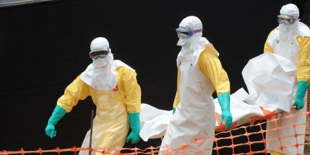 Staff of the 'Doctors without Borders' ('Medecin sans frontieres') medical aid organisation carry the body of a person killed by viral haemorrhagic fever, at a center for victims of the Ebola virus in Guekedou, on April 1, 2014. The viral haemorrhagic fever epidemic raging in Guinea is caused by several viruses which have similar symptoms -- the deadliest and most feared of which is Ebola. AFP PHOTO / SEYLLOU (Photo credit should read SEYLLOU/AFP/Getty Images)