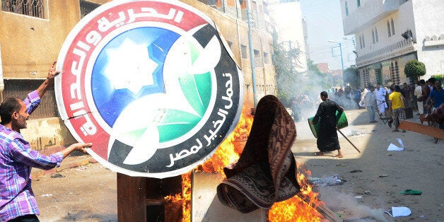 An Egyptian man throws the logo of the Freedom and Justice party, the political arm of the Muslim Brotherhood, into the fire on August 23, 2013 in Mansura. Supporters of ousted Egyptian president Mohamed Morsi began small marches in Cairo in a key test of their ability to mobilise support seven weeks after his overthrow. AFP PHOTO/SAYED BAZ (Photo credit should read SAYED BAZ/AFP/Getty Images)