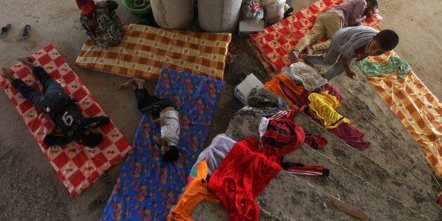 Iraqi Yazidis, who fled their homes a week ago when Islamic State (IS) militants attacked the town of Sinjar, gather inside a building under construction where they found refuge on August 10, 2014 in the Kurdish city of Dohuk in Iraq's autonomous Kurdistan region. 'The Kurdish peshmerga forces have succeeded in making 30,000 Yazidis who fled Mount Sinjar, most of them women and children, cross into Syria and return to Kurdistan,' said Shawkat Barbahari, a Kurdhish official who is in charge of the Fishkhabur crossing with Syria. AFP PHOTO/AHMAD AL-RUBAYE (Photo credit should read AHMAD AL-RUBAYE/AFP/Getty Images)