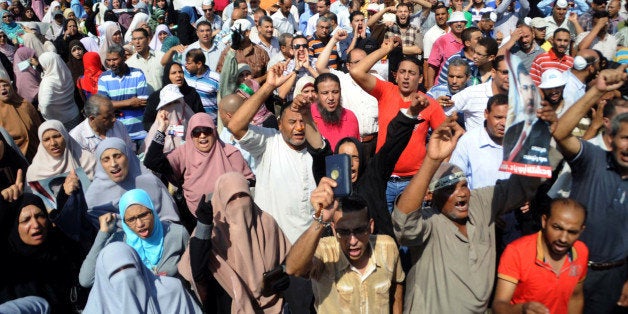 Supporters of the Muslim Brotherhood and Egypt's ousted president Mohamed Morsi chant slogans as they demonstrate in Egypt's northern coastal city of Alexandria on August 14, 2013, against security forces clearing two pro-Morsi protest camps in Cairo. The clearance operation began shortly after dawn when security forces surrounded the sprawling Rabaa al-Adawiya camp in east Cairo and a similar one at Al-Nahda square, in the centre of the capital. AFP PHOTO / STR (Photo credit should read STR/AFP/Getty Images)