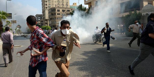Egyptian Muslim Brotherhood supporters run from tear gas fired by Egyptian police as they try to disperse supporters of Egypt's ousted president Mohamed Morsi in a street leading to the Rabaa al-Adawiya protest camp in Cairo on August 14, 2013. Egypt's Muslim Brotherhood said at least 250 people were killed and over 5,000 injured in a police crackdown on two major protest camps held by supporters of ousted president Mohamed Morsi. AFP PHOTO / KHALED DESOUKI (Photo credit should read KHALED DESOUKI/AFP/Getty Images)