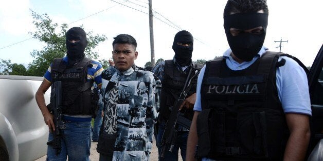 Agents of the Bureau of Criminal Investigation and the Special Response Squad arrest Mara 18's leader Joaquin Garcia, aka 'El Topo', in Tamara, 20 km north of Tegucigalpa on August 13, 2014. AFP PHOTO/Orlando SIERRA (Photo credit should read ORLANDO SIERRA/AFP/Getty Images)