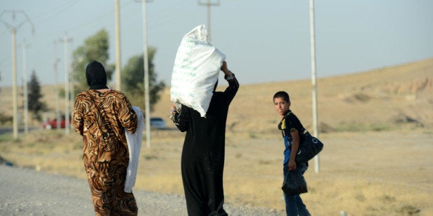 MOSUL, IRAQ - AUGUST 16: Iraqis flee their home as attacks of army groups led by Islamic State (IS), formerly known as ISIL, continue in Mosul city of Iraq on August 16, 2014. Militants from the Islamic State, which then called itself the Islamic State of Iraq and the Levant, or ISIL, captured Mosul in June and then surged across northern Iraq, taking control of several predominantly Sunni cities. Peshmerga, the forces of the Kurdistan Regional Government, have been fighting fierce battles with the heavily armed Islamic State militants. (Photo by Ahmet Izgi/Anadolu Agency/Getty Images)