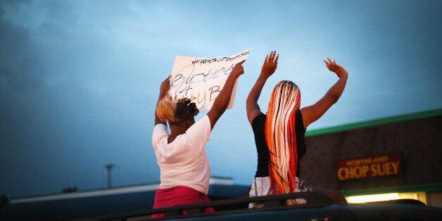 FERGUSON, MO - AUGUST 17: Demonstrators raise their arms during a protest against the killing of teenager Michael Brown on A