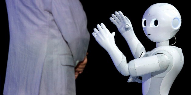 Humanoid robot Pepper, developed by SoftBank Corp.'s Aldebaran Robotics unit, performs next to Masayoshi Son, chairman and chief executive officer of SoftBank Corp., at SoftBank World 2014 in Tokyo, Japan, on Tuesday, July 15, 2014. As Son pushes for a takeover of T-Mobile US Inc., the Japanese billionaire is asking banks to commit financing for a longer-than-usual amount of time, underscoring the intense regulatory review he faces. Photographer: Kiyoshi Ota/Bloomberg via Getty Images