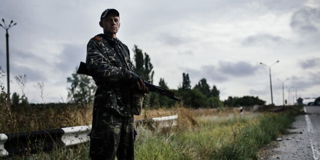 A pro-Russia militant stands guard on a road near Donetsk, on August 18, 2014. Ukraine accused on August 18, 2014 pro-Russian rebels of killing dozens of civilians fleeing the war-torn east as crisis talks between Kiev and Moscow failed to halt months of bloodshed. AFP PHOTO / DIMITAR DILKOFF (Photo credit should read DIMITAR DILKOFF/AFP/Getty Images)