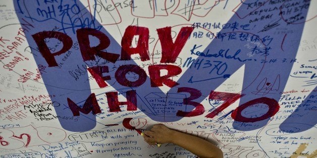 A Malaysia Airlines employee writes a message expressing prayers and well-wishes for passengers onboard missing Malaysia Airlines (MAS) flight MH370 at Kuala Lumpur International Airport in Sepang on March 14, 2014. The needle-in-a-haystack hunt for the missing Malaysian airliner spread to the vast Indian Ocean after the White House cited 'new information' that it might have flown for hours after vanishing nearly seven days ago. AFP PHOTO/ MANAN VATSYAYANA (Photo credit should read MANAN VATSYAYANA/AFP/Getty Images)