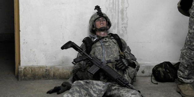 A US soldier from 1st Infantry Division lies exhausted on the floor at an operation post after completing a mission to search for weapons caches in the Alaugal valley in Nishagam, in Afghanistan's eastern Kunar province on April 10, 2009. Obama has pledged to send 17,000 more troops into Afghanistan on top of the 60,000 already here with the NATO-led International Security Assistance Force (ISAF), with most of those are expected to head to the south and east. AFP PHOTO/LIU Jin (Photo credit should read LIU JIN/AFP/Getty Images)