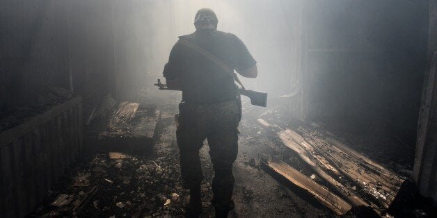 A Pro-Russian rebel walks in a passage at the local market damaged by shelling in Petrovskiy district in the town of Donetsk, eastern Ukraine, Tuesday, Aug. 26, 2014. On Tuesday several shells hit the local market and nearby houses during the mortar duel between Pro-Russian rebels and Ukrainian army. (AP Photo/Mstislav Chernov)