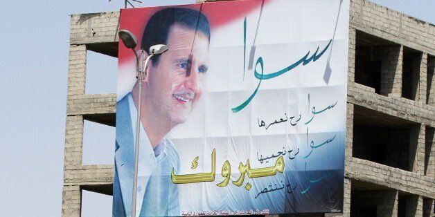 TO GO WITH AFP STORY BY RANA MOUSSAOUIPeople walk past a huge billboard bearing a portrait of Syrian President Bashar al-Assad on July 15, 2014 in the capital Damascus. Assad begins a new seven-year term tomorrow looking to play up a string of battlefield victories while trying to win over war-weary Syrians and those fearful of jihadists. AFP PHOTO / LOUAI BESHARA (Photo credit should read LOUAI BESHARA/AFP/Getty Images)