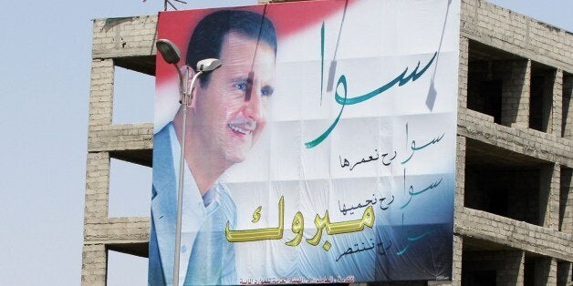TO GO WITH AFP STORY BY RANA MOUSSAOUI
People walk past a huge billboard bearing a portrait of Syrian President Bashar al-As