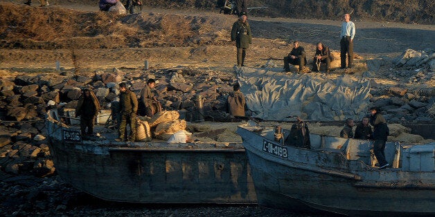 North Korean workers and soldiers sit on the banks of the Yalu River at the town of Sinuiju across from the Chinese border to