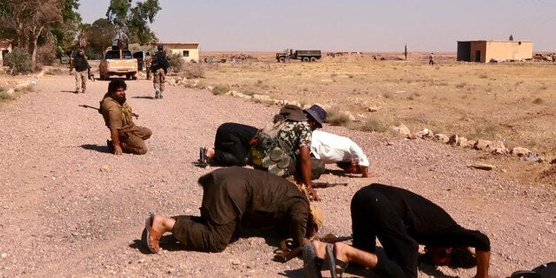 This undated image posted Wednesday, Aug. 27, 2014 by the Raqqa Media Center of the Islamic State group, a Syrian opposition group, which has been verified and is consistent with other AP reporting, shows fighters from the Islamic State group that captured the Tabqa air base from the Syrian government on Sunday, praying inside the air base, in Raqqa, Syria. A U.N. commission on Wednesday accused the extremist Islamic State organization of committing crimes against humanity with attacks on civilians, as pictures emerged of the extremists' bloody takeover of a Syrian military air base that added to the international organizationâs claims. (AP Photo/ Raqqa Media Center of the Islamic State group)