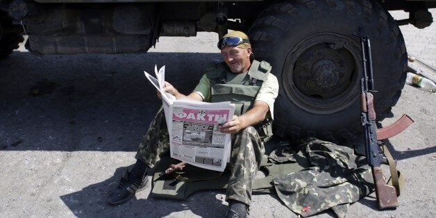 A Ukrainian soldier reads a newspaper at a checkpoint in the eastern city of Debaltseve on August 6, 2014. Russian President