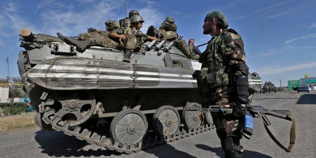 A pro-Russian rebel watches as Ukrainian troops evacuate from the rebel-held town of Starobesheve, eastern Ukraine, Saturday,