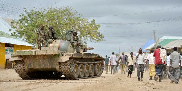 In this photo provided by the African Union Mission to Somalia (AMISOM), African Union (AU) soldiers from Uganda sit on their tank as residents walk past in the town of Bulomarer, in the Lower Shabelle region of Somalia Sunday, Aug. 31, 2014. Somali government and AU troops drove al-Shabab militants from their stronghold of Bulomarer on Saturday as part of their military offensive dubbed "Indian Ocean" aiming to oust al-Shabab from its last major hideouts in the southern parts of the Horn of Africa nation. (AP Photo/AMISOM, Tobin Jones)