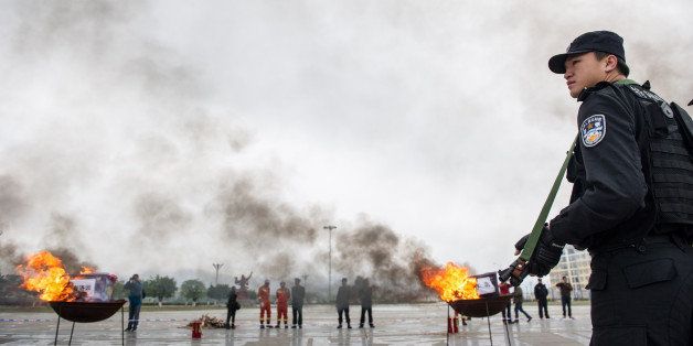 Police forces watch as drugs burn in huge iron pots during a ceremony in Ningming county of Chongzuo, southwest China's Guangxi Zhuang autonomous region on March 10, 2014. A total of 1,000 kilograms of drugs, seized in China-Vietnam joint anti-drug campaigns in border areas since 2013, were destroyed in the ceremony, state media reported. CHINA OUT AFP PHOTO (Photo credit should read STR/AFP/Getty Images)