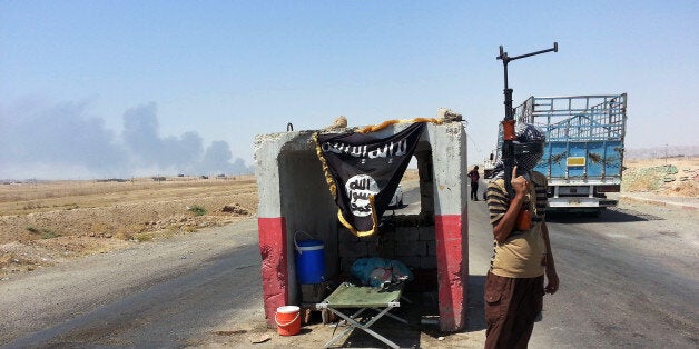 FILE - In this file photo taken Thursday, June 19, 2014, an al-Qaida-inspired militant stands guard at a checkpoint captured from the Iraqi Army outside Beiji refinery, some 250 kilometers (155 miles) north of Baghdad, Iraq. The al-Qaida breakaway group that has seized much of northern Syria and huge tracks of neighboring Iraq formally declared the creation of an Islamic state on Sunday, June 29, in the territory under its control. (AP Photo, File)