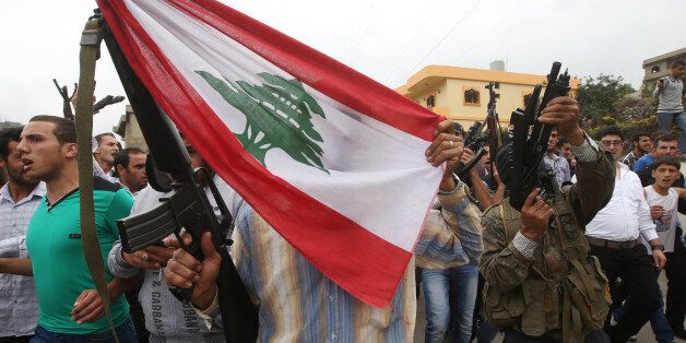 Lebanese Sunni gunmen hold their weapons and a Lebanese flag during the funeral procession of Sgt. Ali Sayid, who was beheaded by Islamic militants, in his home town of Fnaydek, in Akkar north Lebanon, on Wednesday, Sept. 3, 2014. Sgt. Ali Sayid went missing around the same time that some two dozen soldiers and police were seized by militants from Syria who overran the border town of Arsal for several days last month. The incursion was the most serious spillover yet of the Syrian civil war and escalated tensions in Lebanon, which is bitterly split over the conflict. (AP Photo/Hussein Malla)