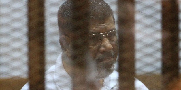 Egypt's deposed Islamist president Mohamed Morsi, charged along with 130 others of plotting attacks and escaping from prison in 2011, sits inside the defendants cage during his trial at the police academy in Cairo on August 18, 2014. Morsi and several leaders from his Muslim Brotherhood have been put on trial on charges that could lead to the death penalty. AFP PHOTO / STR (Photo credit should read STR/AFP/Getty Images)