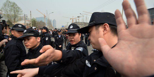 Police officers block journalists from grieving Chinese relatives of passengers on the missing Malaysia Airlines flight MH370 as they gather to protest outside the Malaysian embassy in Beijing on March 25, 2014. Irate Chinese relatives of passengers aboard the crashed Flight MH370 scuffled with security personnel outside Malaysia's embassy on March 25, demanding answers about the plane's mysterious and lonely demise in the stormy Indian Ocean. AFP PHOTO / Mark RALSTON (Photo credit should read MARK RALSTON/AFP/Getty Images)
