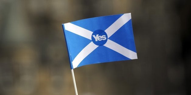 A pro-independence supporter holds a 'Yes' flag as Scottish MP Jim Murphy addresses pro-union 'Better Together' campaign supp