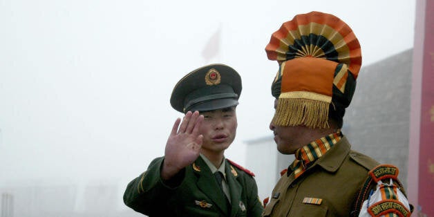 In this photograph taken on July 10, 2008, A Chinese soldier gestures as he stands near an Indian soldier on the Chinese side of the ancient Nathu La border crossing between India and China. When the two Asian giants opened the 4,500-metre-high (15,000 feet) pass in 2006 to improve ties dogged by a bitter war in 1962 that saw the route closed for 44 years, many on both sides hoped it would boost trade. Two years on, optimism has given way to despair as the flow of traders has shrunk to a trickle because of red tape, poor facilities and sub-standard roads in India's remote northeastern mountainous state of Sikkim. AFP PHOTO/Diptendu DUTTA (Photo credit should read DIPTENDU DUTTA/AFP/Getty Images)