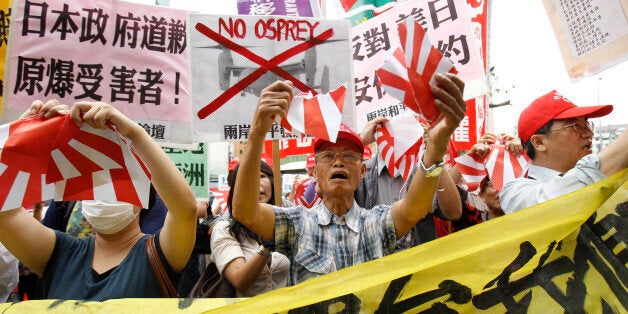 Anti-Japan protesters tear Japanese military flags during a demonstration over what they say is a growing Japanese aggression on fishing waters in East China Sea near a group of Japanese-controlled disputed islands called Senkaku by Japan and Diaoyu by China, also claimed by China and Taiwan, outside the Japanese trade office in Taipei, Taiwan, Thursday, Aug. 15, 2013. The protest was to mark the 68th anniversary of Japan's surrender in World War II. (AP Photo/Wally Santana)