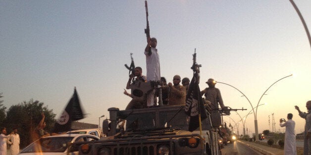 In this photo taken Monday, June 23, 2014, fighters of the al-Qaida-inspired Islamic State of Iraq and the Levant (ISIL) parade in a commandeered Iraqi security forces armored vehicle down a main road at the northern city of Mosul, Iraq, more than two weeks after ISIL took over the country's second largest city. U.S. Secretary of State John Kerry warned Mideast nations on Wednesday against taking new military action in Iraq that might heighten already-tense sectarian divisions, as reports surfaced that Syria launched airstrikes across the border and Iran has been flying surveillance drones over the neighboring country. (AP Photo)