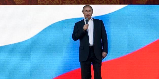 Russian President Vladimir Putin, with Russian flag as background, speaks at a ceremony marking the 100th anniversary of Tyva joining Russia in Kyzyl, the capital of the Tyva region, southern Siberia, about 4,700 kilometers (2,900 miles) southeast of Moscow, Russia, Saturday, Sept. 6, 2014. (AP Photo/RIA-Novosti, Alexei Nikolsky, Presidential Press Service)