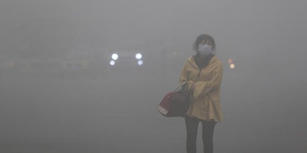 A woman wearing a face mask walks in heavy smog in Harbin, northeast China's Heilongjiang province, on October 21, 2013. Choking clouds of pollution blanketed Harbin, a Chinese city famed for its annual ice festival on October 21, reports said, cutting visibility to 10 metres (33 feet) and underscoring the nation's environmental challenges. CHINA OUT AFP PHOTO (Photo credit should read STR/AFP/Getty Images)