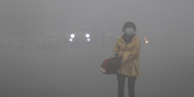 A woman wearing a face mask walks in heavy smog in Harbin, northeast China's Heilongjiang province, on October 21, 2013. Choking clouds of pollution blanketed Harbin, a Chinese city famed for its annual ice festival on October 21, reports said, cutting visibility to 10 metres (33 feet) and underscoring the nation's environmental challenges. CHINA OUT AFP PHOTO (Photo credit should read STR/AFP/Getty Images)