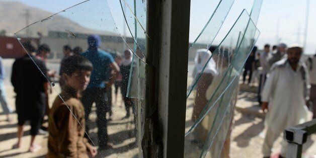 Afghans are seen through broken glass at a shop at the site of a suicide attack in Kabul on July 22, 2014. A Taliban suicide attacker riding a motorbike killed at least four foreigners in a compound in Kabul on July 22, police said, in the latest blast to rock the capital during a prolonged impasse over presidential election results. AFP PHOTO/SHAH Marai (Photo credit should read SHAH MARAI/AFP/Getty Images)
