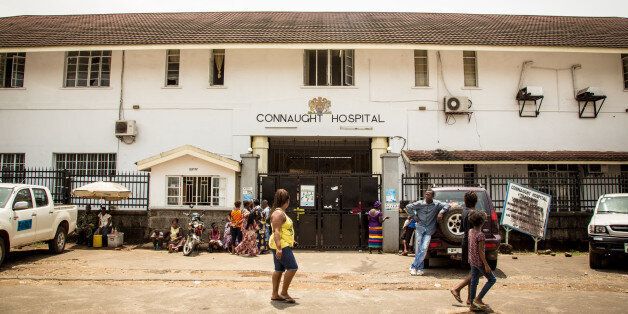 In this photo taken on Sunday, Sept. 14, 2014, people walk past the Connaught Hospital that is used for treating people suffering from the Ebola virus in Freetown, Sierra Leone. Shoppers crowded streets and markets in Sierra Leone's capital on Thursday, Sept. 18, stocking up for a three-day shutdown that authorities hope will slow the spread of the Ebola outbreak that is accelerating across West Africa. (AP Photo/ Michael Duff)