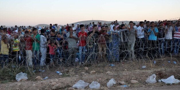 SANLIURFA, TURKEY - SEPTEMBER 19: Syrians gathering on Turkish-Syrian border for the last two days after fleeing attacks from Islamic State and the Levant (ISIL) in the Ar-Raqqah Governorate of Syria, wait to cross the border into Suruc district of Turkey's Sanliurfa province on September 19, 2014. (Photo by Esber Ayaydin/Anadolu Agency/Getty Images)