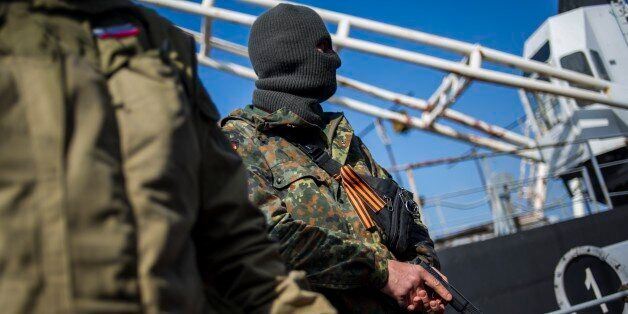 A man in an unmarked uniform with a ribbon symbolizing the Soviet victory in WWII, holds a gun during seizure of the Ukrainian corvette Khmelnitsky in Sevastopol, Crimea, Thursday, March 20, 2014. Pro-Russian crowds seized two Ukrainian warships Thursday. Shots were fired but there were no casualties as the Ukrainian corvette Khmelnitsky was seized in Sevastopol. Another ship, the Lutsk, was also surrounded by pro-Russian forces. (AP Photo/Andrew Lubimov)
