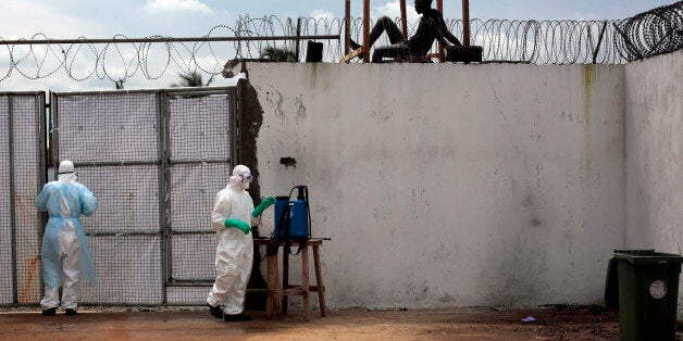 Health workers stand outside the Island Clinic Ebola isolation and treatment center in Monrovia, Liberia, Friday Sept. 26, 2014. The outbreak of Ebola has overwhelmed the weak health systems of some of the world's poorest countries - there aren't enough doctors and nurses or even clinics to treat the spiraling number of cases.(AP Photo/Jerome Delay)