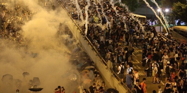 Police fire tear gas upon pro-democracy demonstrators near the Hong Kong government headquarters on September 28, 2014. Police fired tear gas as tens of thousands of pro-democracy demonstrators brought parts of central Hong Kong to a standstill Sunday, in a dramatic escalation of protests that have gripped the semi-autonomous Chinese city for days. AFP PHOTO / AARON TAM (Photo credit should read aaron tam/AFP/Getty Images)