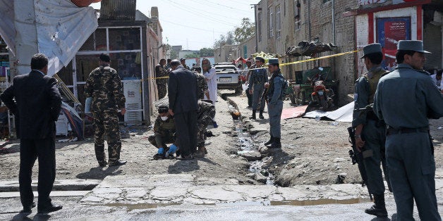 Afghan security forces inspect the site of a suicide attack near the International Airport of Kabul, Afghanistan, Monday, Sept. 29, 2014. Two bomb attacks took place on the road connecting the country's main airport with the palace. One roadside bomb did not result in any deaths or injuries, but a second attack about a kilometer (half mile) from the airport by a suicide bomber killed several, police officer Abdul Latif said. (AP Photo/Massoud Hossaini